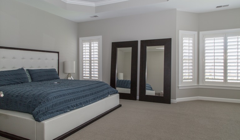Polywood plantation shutters work well with minimalist design. White shutters in a minimalist bedroom in Philadelphia.
