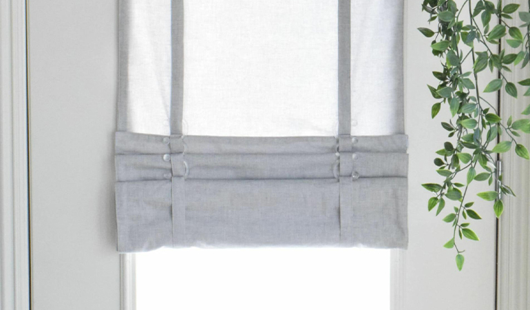 With a tiered tumble shade in Philadelphia, you can block sun glare all year round. Gray rolled tumble shade on a glass door
